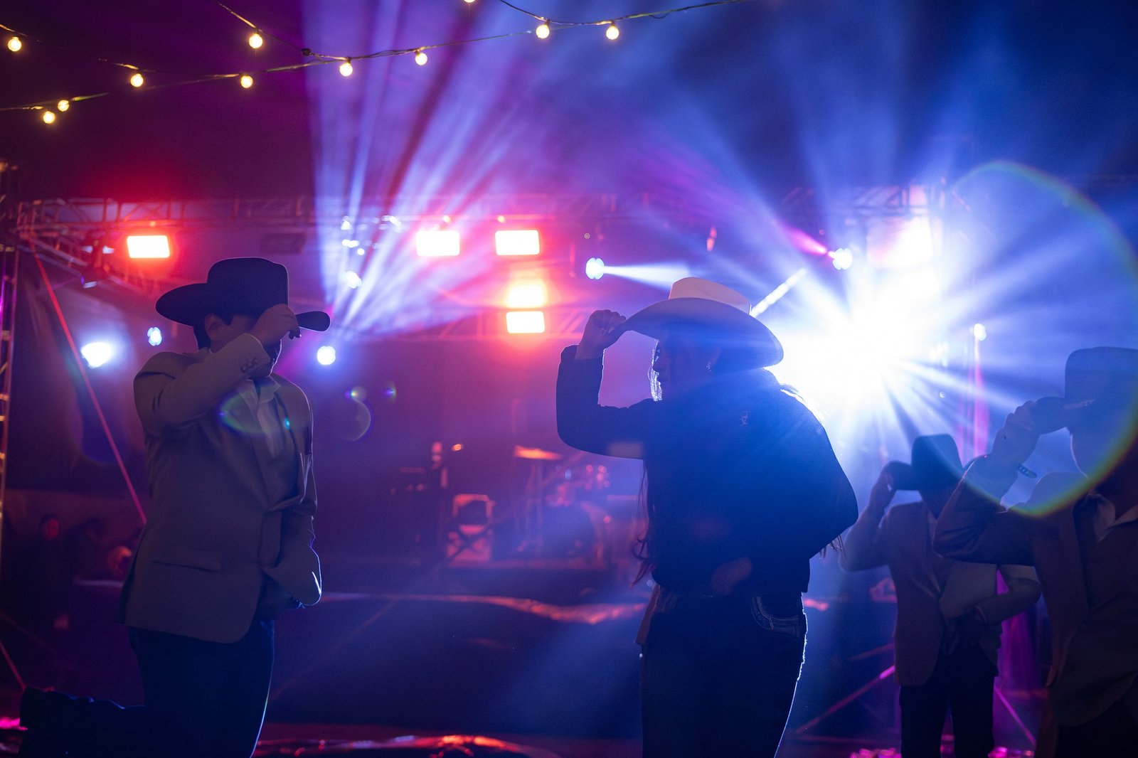 Siluetas bailando entre las luces del escenario en un evento nocturno