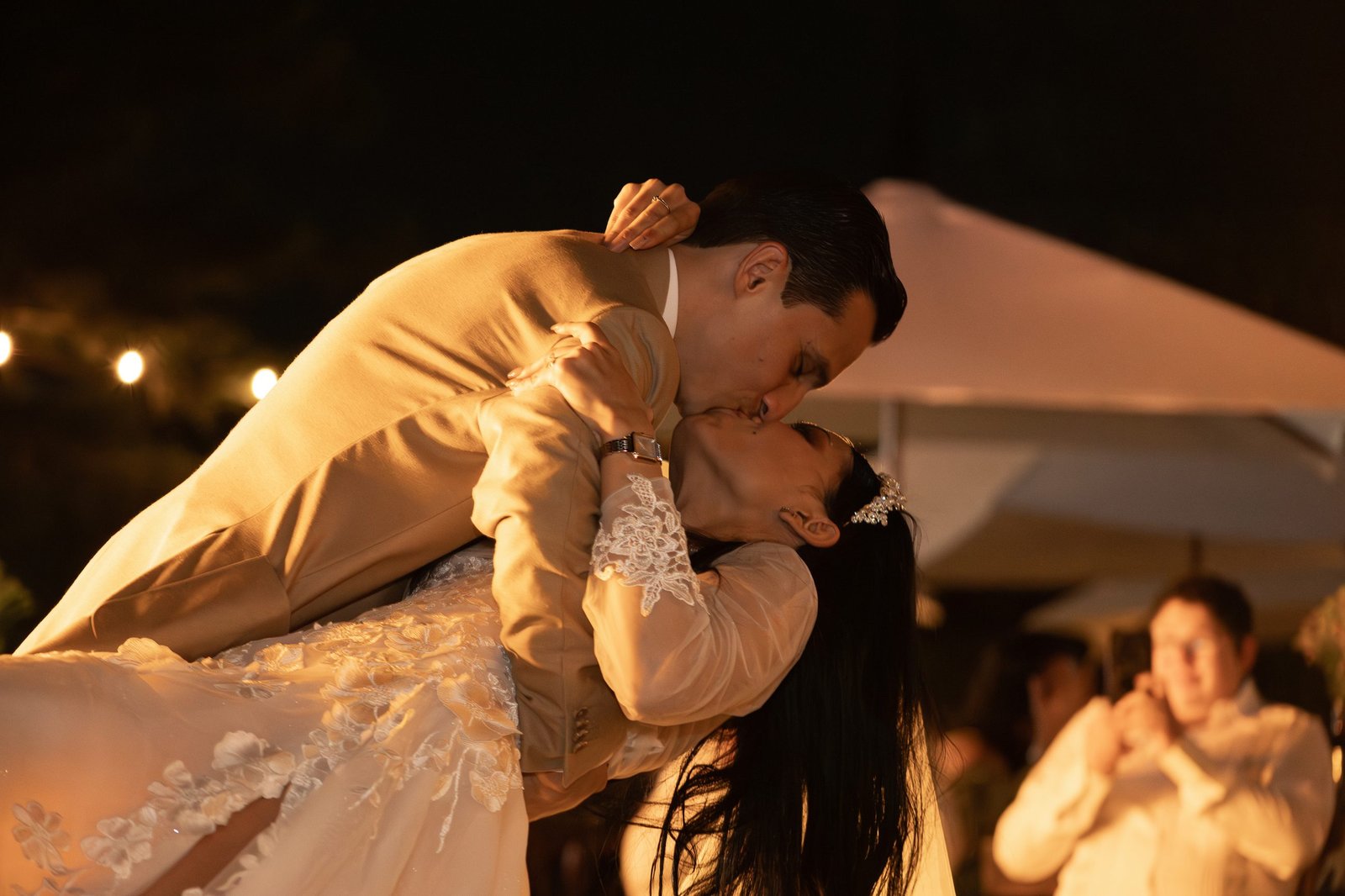 Los novios besándose durante el primer baile, bajo luz cálida