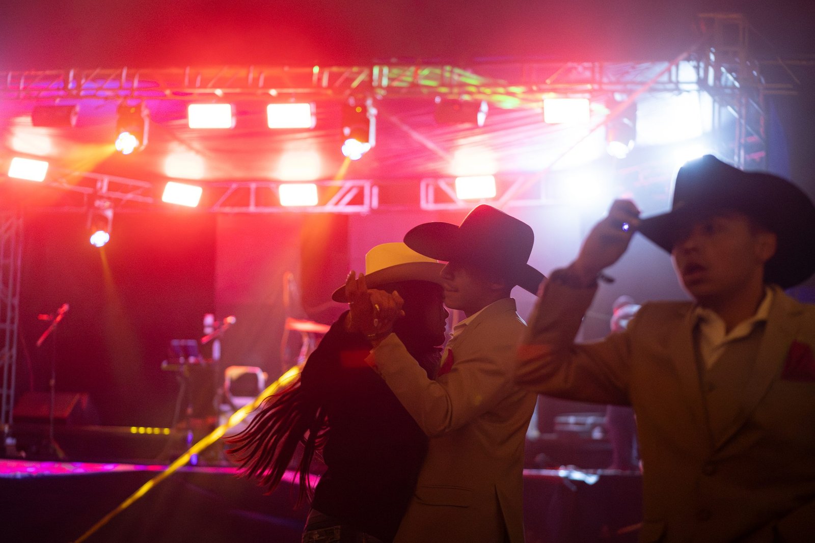 Parejas bailando con sombrero frente a las luces del escenario