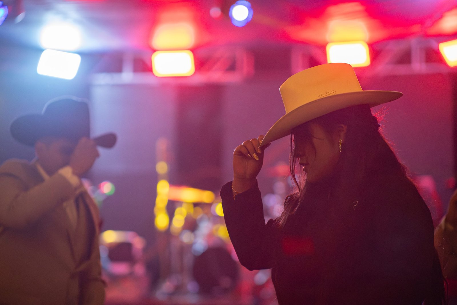Mujer con sombrero blanco entre las luces de un evento nocturno